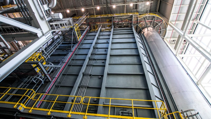 Large metal power plant stacks with yellow railings.