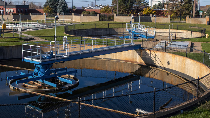 Water reclamation tanks with skimming arms and green grass between tanks