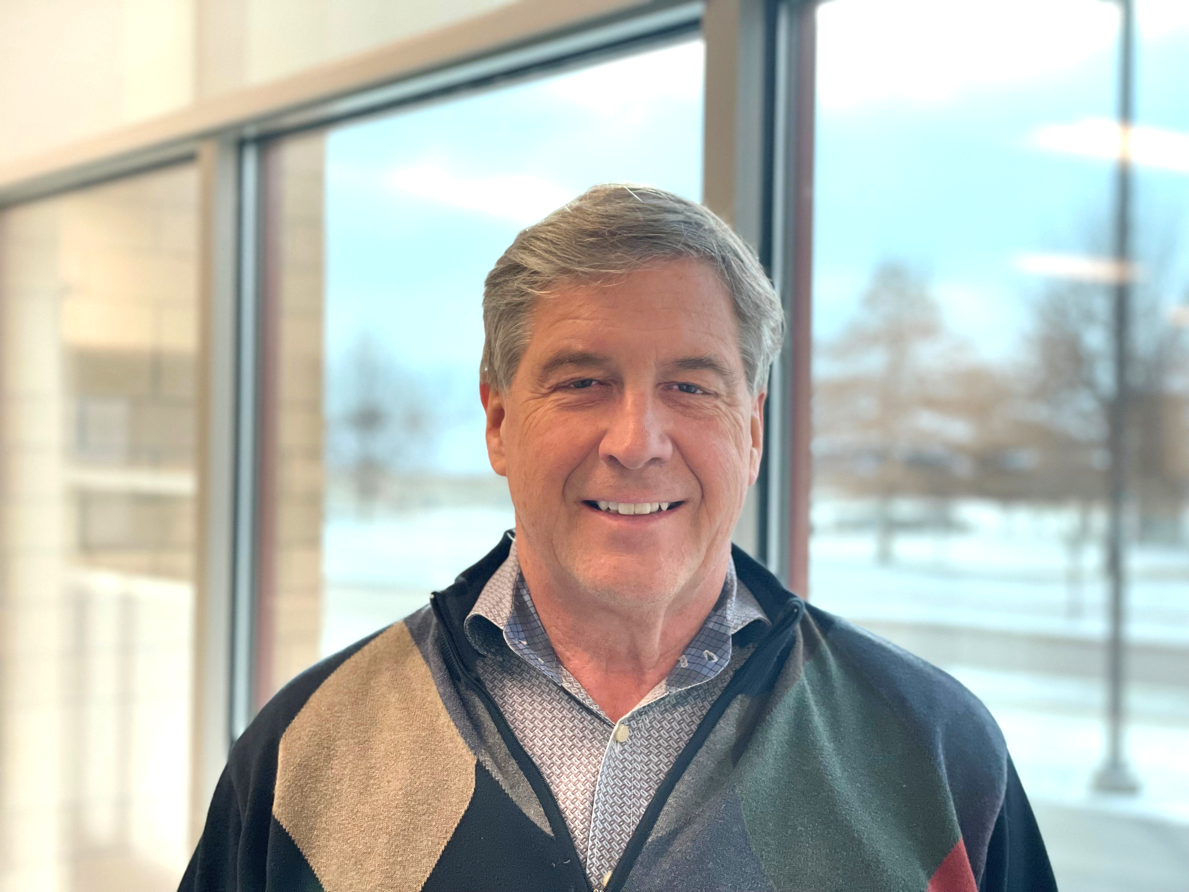 male executive wearing a green sweater with a diamond pattern