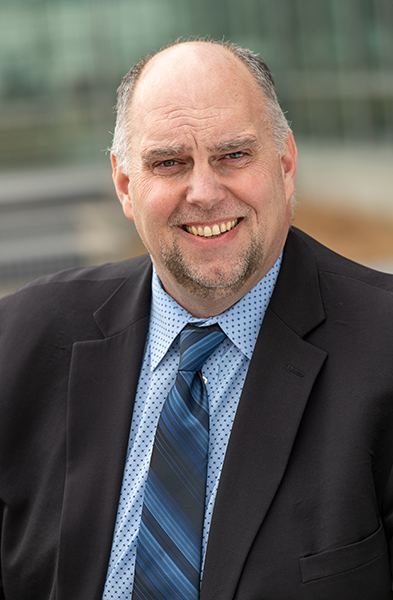 male executive wearing a dark jacket, blue shirt and a blue tie