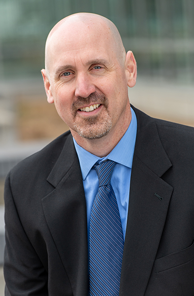 male executive wearing a black jacket, blue shirt and blue tie