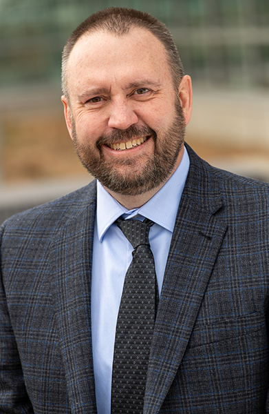 male executive wearing a blue jacket, blue shirt and a dark tie