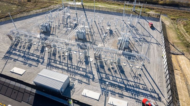 Final construction on East Point substation with transformers and electrical bussing in place. Two red trucks are parked inside the fence.