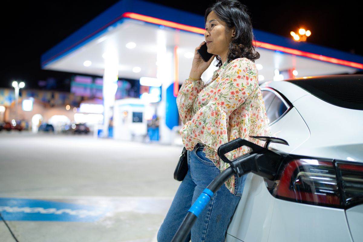 Woman calls someone on the phone while waiting for her EV to charge
