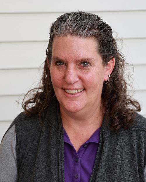 female executive wearing a black jacket purple collared shirt