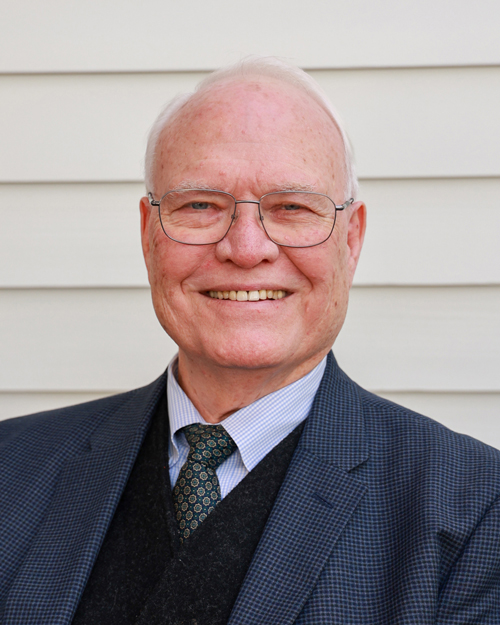 male executive wearing a grey jacket, blue shirt and blue tie with a black sweater