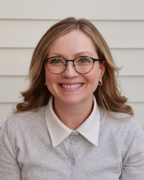 Female executive wearing glasses and a grey sweater over a white button down