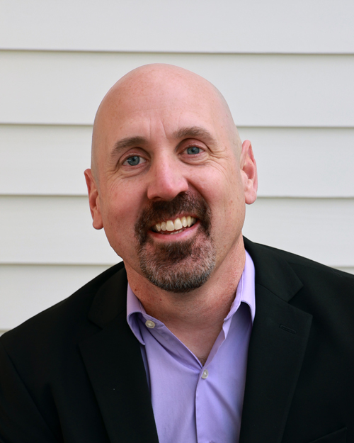 male executive wearing a black jacket and purple button down