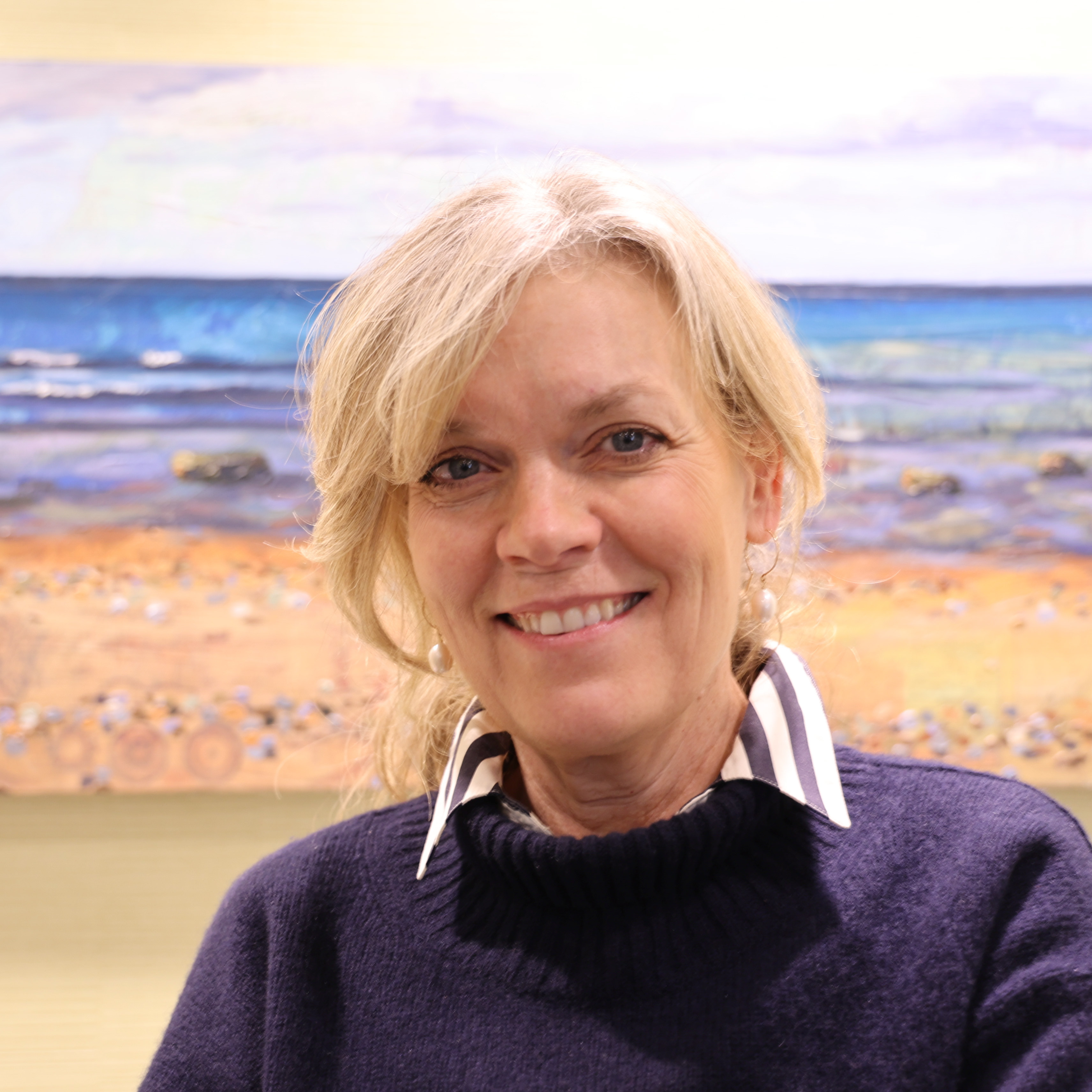 female executive wearing a black sweater over a striped collared shirt