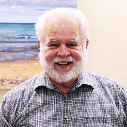 male executive with white beard wearing a plaid shirt