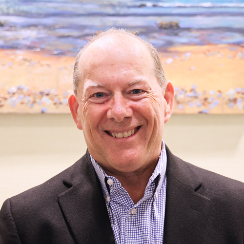 male executive wearing a black suit coat and plaid shirt