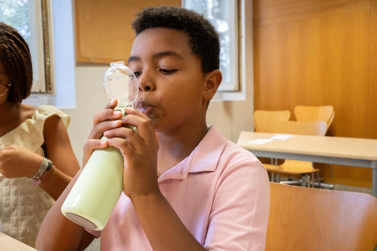 School-aged boy drinking from a water bottle at a desk