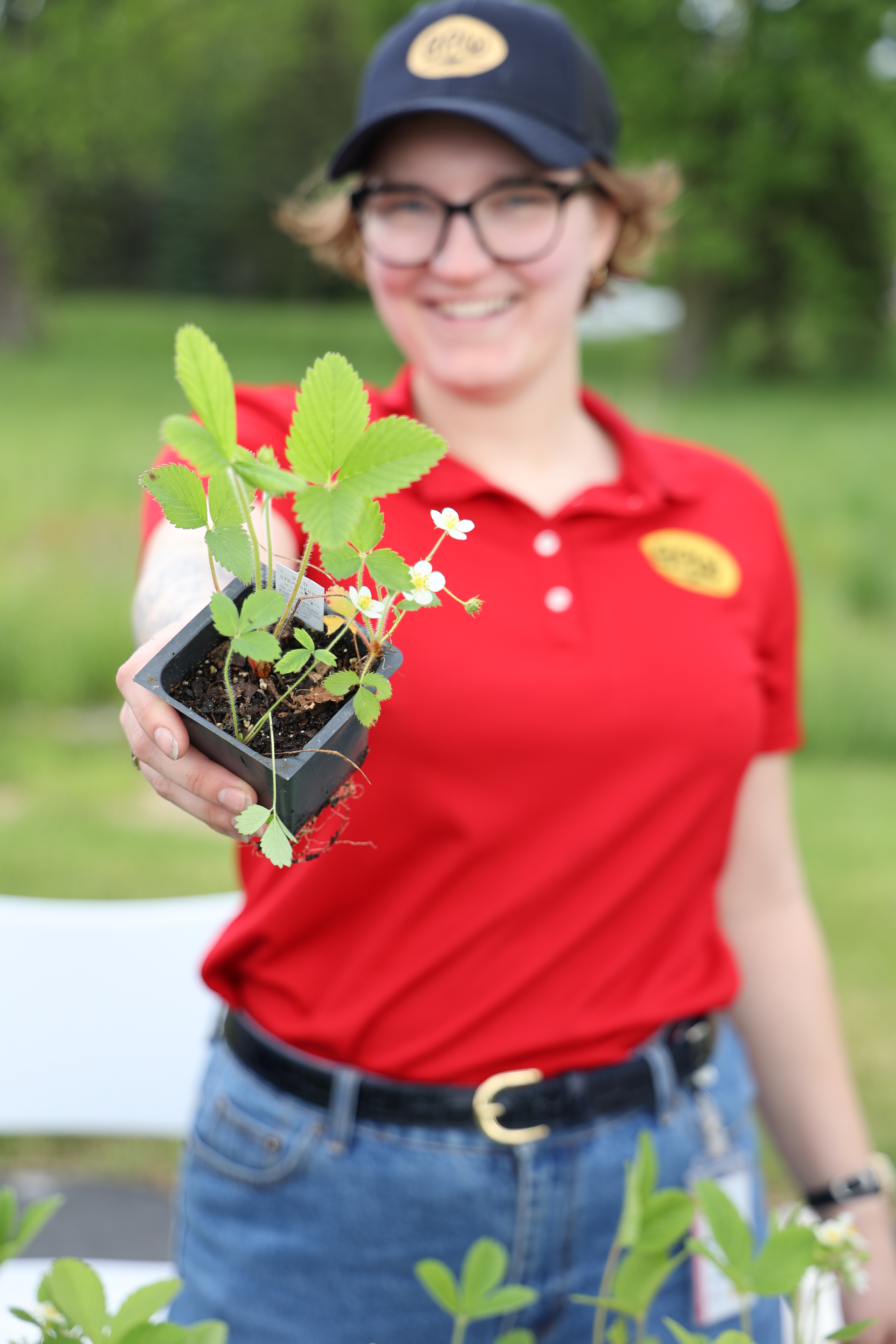 girl in red shirt holding out a native plant