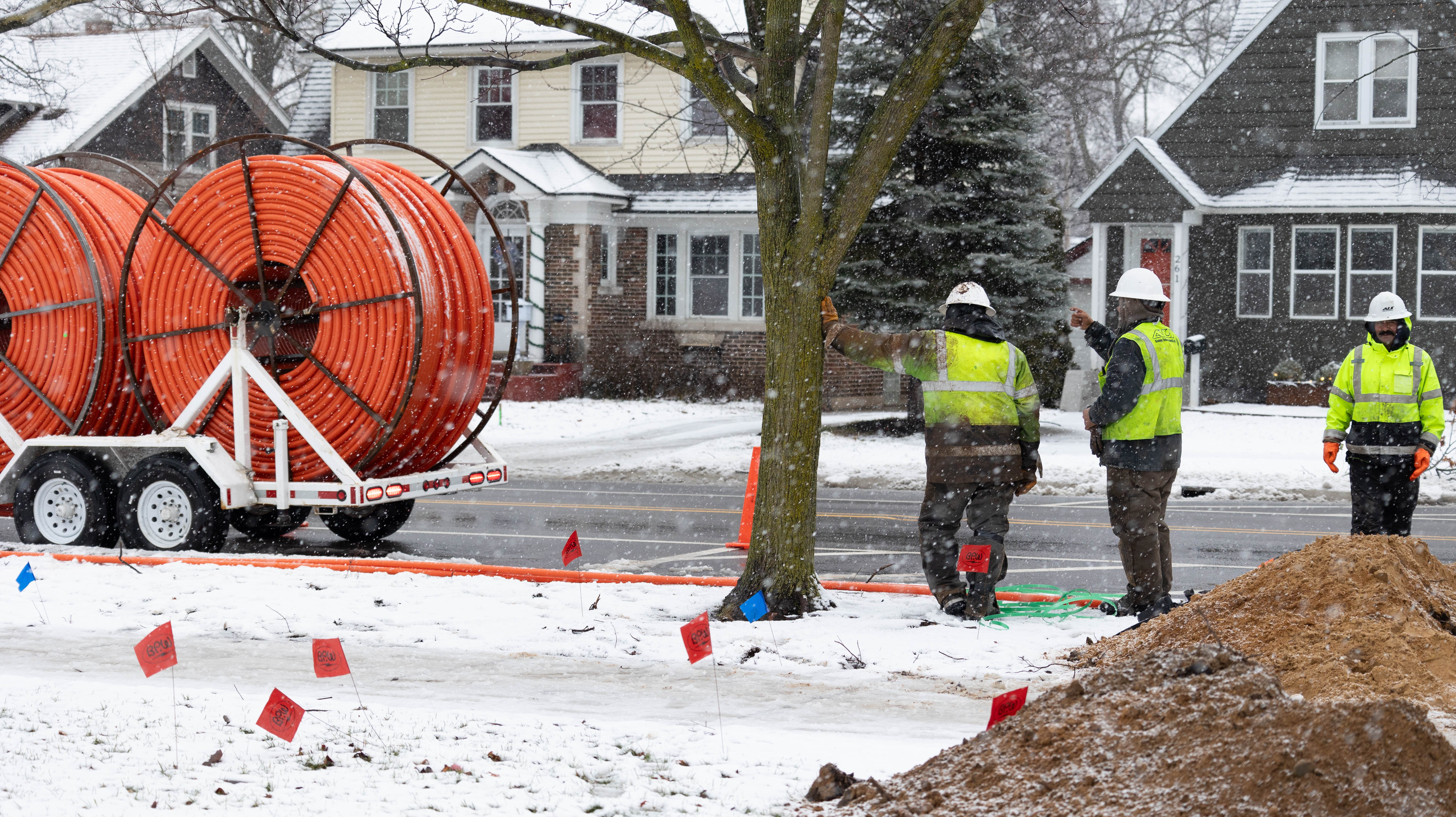 construction workers walking towards spools of orange conduit